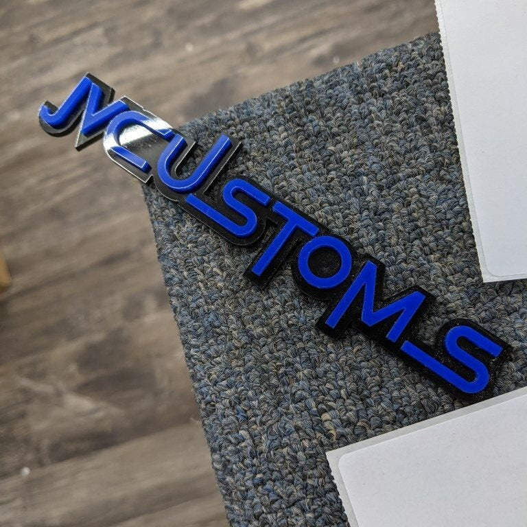 JVCustoms Car Badge - Blue On Gloss Black - Squid Font - Tape Mount - Atomic Car Concepts