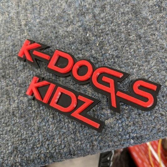 K Dogs Kidz Car Badge - Red On Matte Black - Squid Font - Tape Mount - Atomic Car Concepts