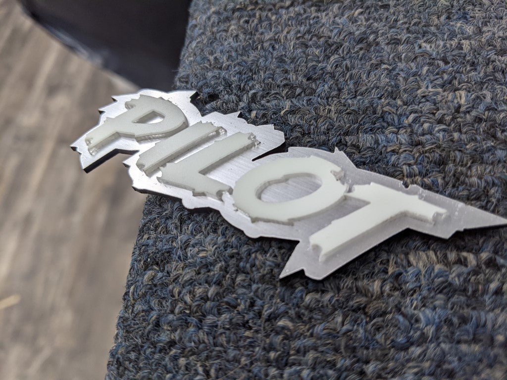 Pilot Car Badge - White On Brushed Silver - Lightning Font - Atomic Car Concepts