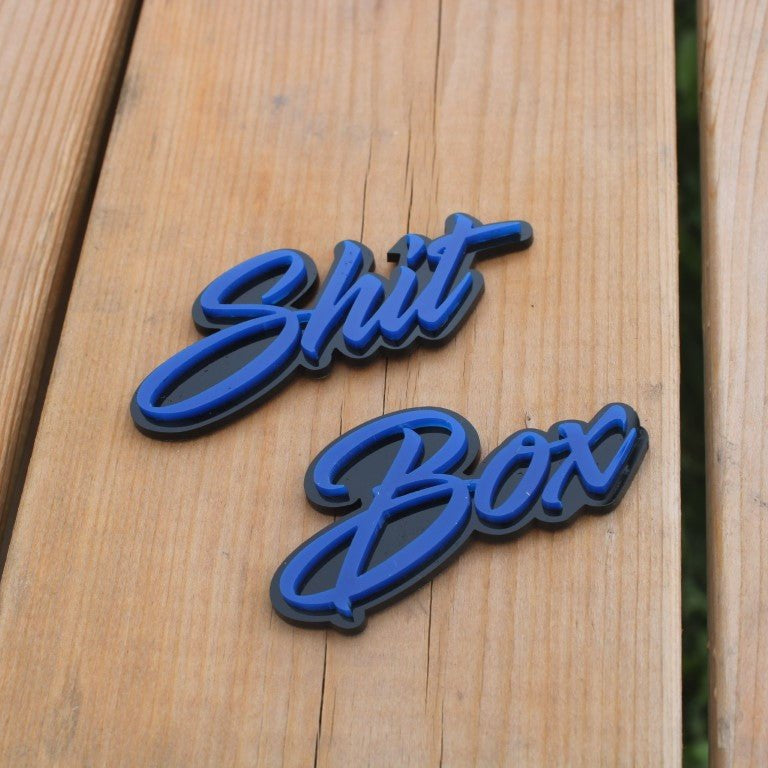 Shit Box Car Badge - Blue On Matt Black - Script Font - Atomic Car Concepts