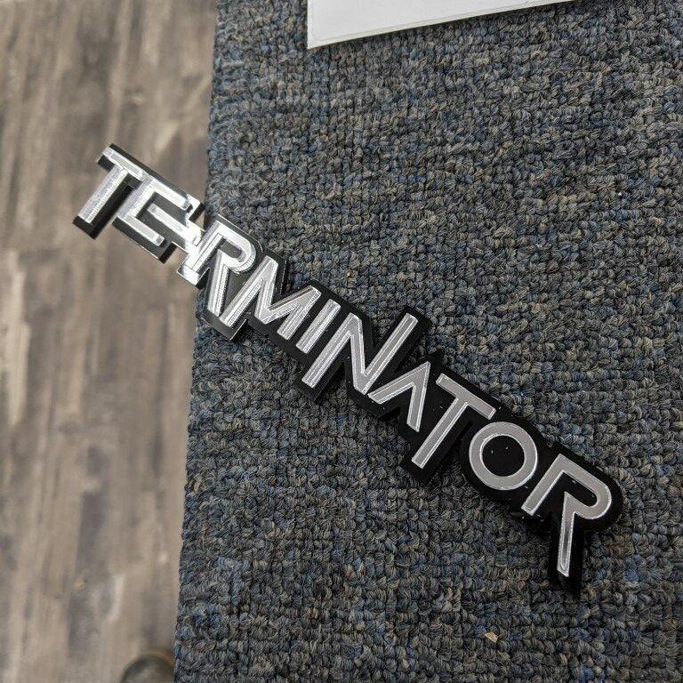 Terminator Car Badge - Mirror Silver On Gloss Black - Squid Font - Tape Mount - Atomic Car Concepts