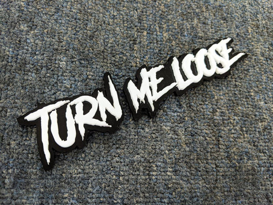 Turn Me Loose Car Badge - White on Gloss Black - Aggressive Font - Tape Mounting - Atomic Car Concepts